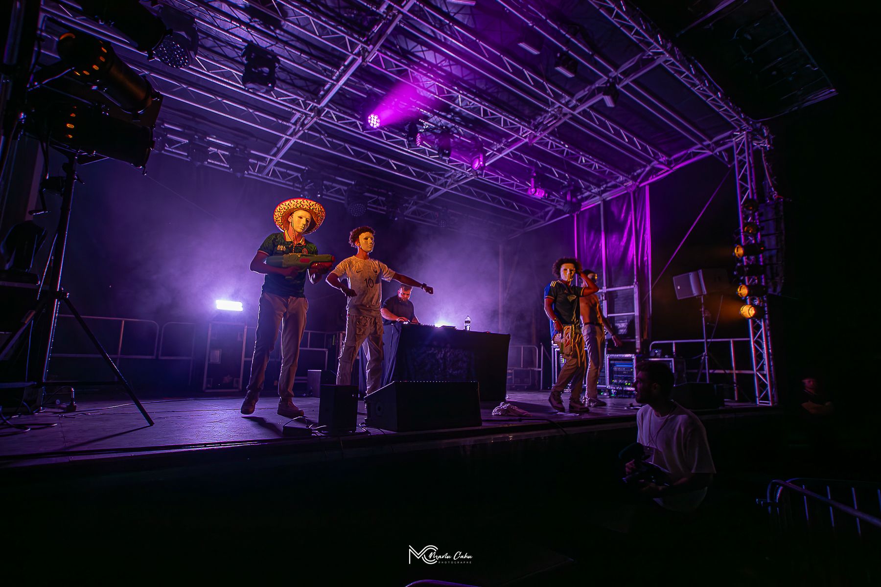 Scène sous lumière violette avec danseurs masqués